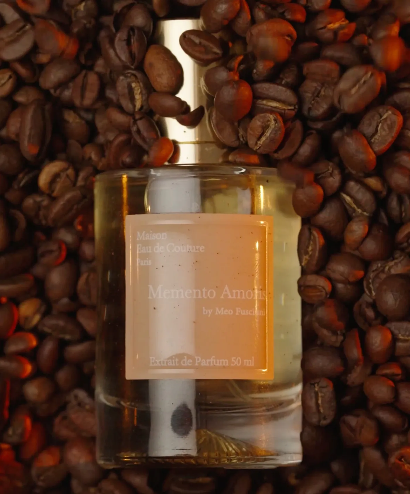 Flacon du parfum Memento Amoris posé sur des grains de café